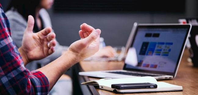 Persoonsgegevens bewaren - Man achter laptop, maakt gebruik van zijn handen om iets duidelijk te maken